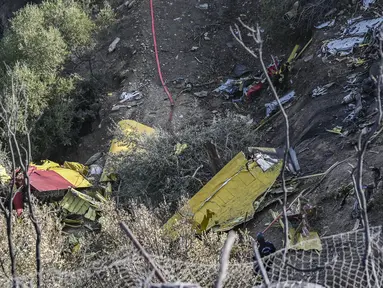 Perwira militer dan petugas pemadam kebakaran mencari puing-puing pesawat pemadam kebakaran Canadair CL-215, yang jatuh di dekat lokasi saat diterbangkan untuk memadamkan kebakaran hutan di Karystos, di pulau Aegean Yunani Evia, Selasa (25/7/2023). (STRINGER / AFP)