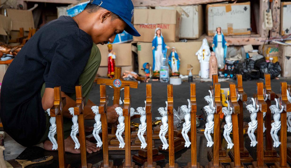 Seorang pekerja membungkus patung keagamaan Kristen di bengkel kerajinan Studio Malta Jaya di Bantul, Yogyakarta, pada Kamis 18 Desember 2025. (DEVI RAHMAN/AFP)