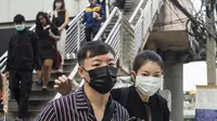 Pekerja mengenakan masker usai menaiki komuter selama kabut asap menyelimuti Bangkok (16/1). Thailand telah berupaya untuk mengatasi polusi yang telah menyelimuti ibukota dalam beberapa pekan terakhir. (AFP Photo/Romeo Gacad)