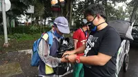 Salah seorang pentolan VIking Persib Club Yana Umar membagikan masker dan sembako kepada warga yang membutuhkan. (Dok Viking Persib Club)