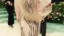 Lana Del Rey mengenakan gaun dari Alexander McQueen. Ia pun tampil sesuai dengan tema dengan siluet cabang-cabang pohon yang menyembul dari kanopi tulle. Dengan gaun tube coklat yang memiliki aksen motif akar. [@alexandermcqueen]