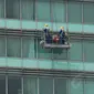 Pekerja terlihat tengah membersihkan kaca gedung di Bundaran HI, Jakarta, dengan menggunakan gondola, Senin (8/9/14). (Liputan6.com/Johan Tallo)
