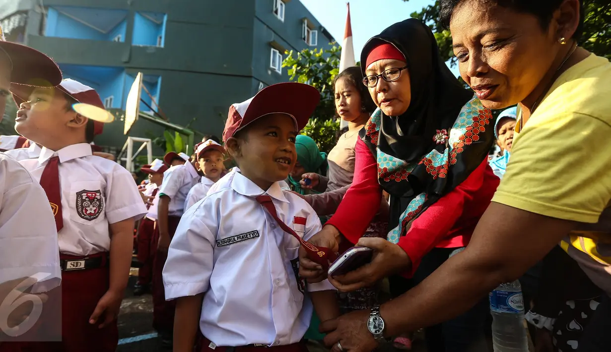Orangtua merapikan seragam anaknya sebelum upacara pada hari pertama sekolah di SDN Pasar Baru 05 Jakarta, Senin (18/7). Usai libur Idul Fitri, para siswa kembali mengikuti pelajaran di sekolah untuk tahun ajaran 2015-2016. (Liputan6.com/Faizal Fanani)
