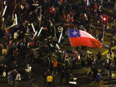 Seorang Suporter membawa bendera nasional Chile di kerumunan merayakan kemenangan Chile atas Uruguay di Copa America 2015 di Santiago, Chile, (25/6/2015). Chile melaju ke semifinal usai mengalahkan Uruguay 1-0. (REUTERS/Catherine Allen)