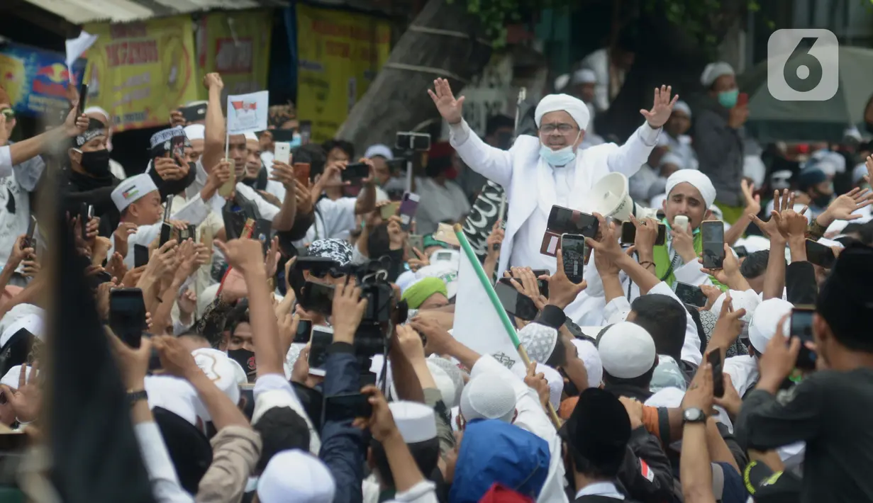 Rizieq Shihab menyapa massa pendukungnya saat tiba di kediamannya di Jalan Petamburan, Jakarta, Selasa (10/11/2020). Rizieq Shihab tiba di kediamannya usai pulang dari Arab Saudi. (merdeka.com/Imam Buhori)