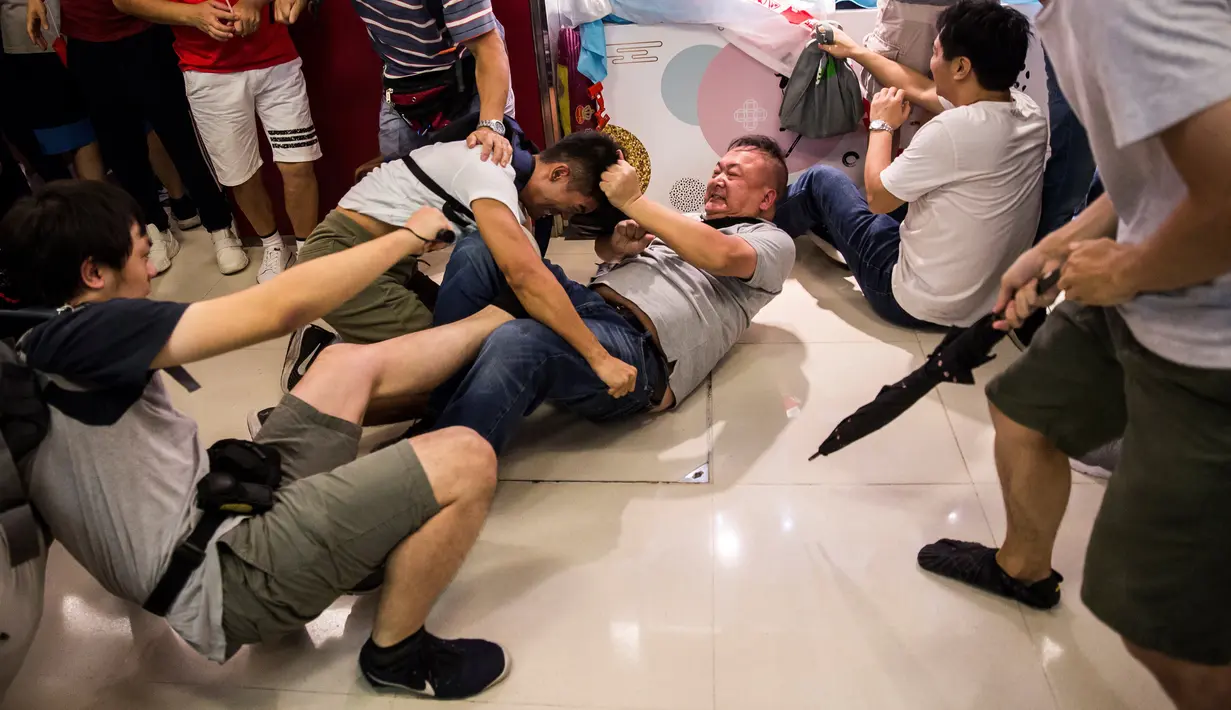 Demonstran pro-China (kanan) berkelahi dengan demonstran antipemerintah di sebuah pusat perbelanjaan di Distrik Kowloon Bay, Hong Kong, Sabtu (14/9/2019). Bentrokan yang awalnya hanya adu mulut berubah menjadi saling baku pukul. (ISAAC LAWRENCE/AFP)