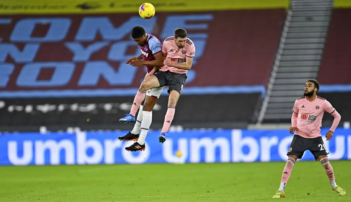 Pemain West Ham United Ben Johnson (kiri) berebut bola udara dengan pemain Sheffield United Chris Basham pada pertandingan Liga Inggris di London Stadium, London, Inggris, Senin (15/2/2021). West Ham United menang 3-0. (Justin Setterfield/Pool via AP)