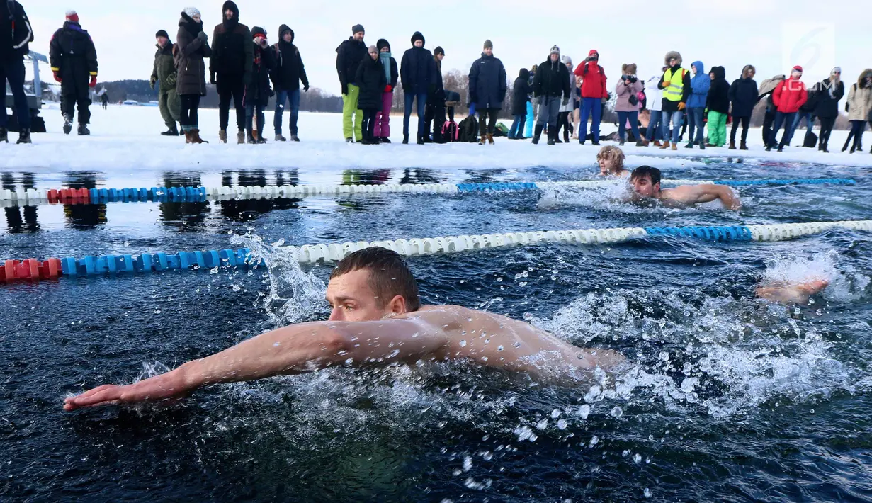 Peserta saat mengikuti kompetisi renang musim dingin tahunan dengan air es beku di Trakai, Lituania (24/2). Para peserta tetap antusias mengikuti lomba walaupun dengan suhu di luar hingga minus 12 derajat Celcius. (AFP Photo/Petras Malukas)