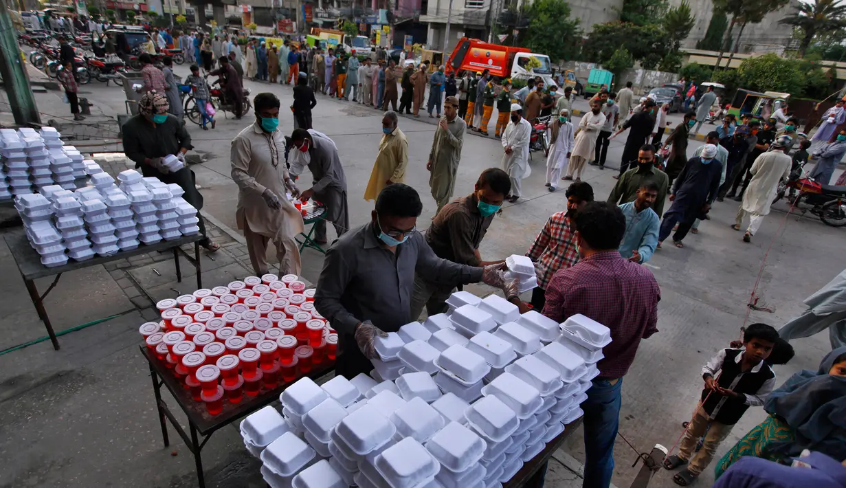 Relawan membagikan makanan dan minuman manis tradisional untuk orang-orang berbuka puasa, di Rawalpindi, Pakistan, Minggu, (3/5/2020). Umat Muslim di seluruh dunia sedang melaksanakan Ramadan untuk menahan diri dari makan, minum sejak subuh sampai senja. (AP/Anjum Naveed)