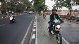 Pengendara sepeda motor melintasi trotoar Danau Sunter, Jakarta, Senin (22/7/2019). Tidak adanya fasilitas parkir di kawasan tersebut menyebabkan pengunjung Danau Sunter memarkirkan sepeda motor mereka di sepanjang trotoar sehingga mengganggu akses pejalan kaki. (merdeka.com/Iqbal Nugroho)