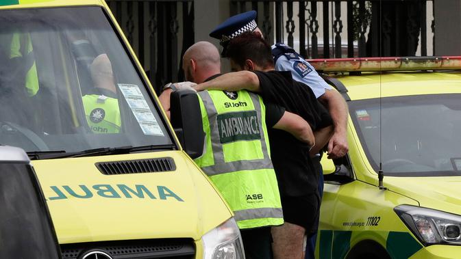 Polisi dan staf ambulans membantu seorang lelaki yang terluka dalam insiden penembakan di Masjid Al Noor, Christchurch, Selandia Baru, Jumat (15/3). Tiga korban penembakan adalah perempuan dewasa dan seorang lagi adalah gadis cilik. (AP Photo/Mark Baker)