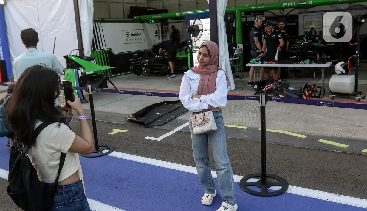Beberapa penonton menyempatkan berfoto berlatar paddock Formula E. Balapan utama Jakarta E-Prix 2025 akan berlangsung pada Sabtu 21 Juni 2025 sore dan mengambil tajuk Sarinah Jakarta E-Prix 2025. (Liputan6.com/Herman Zakharia)