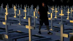 Seorang pria berjalan dekat kuburan tentara yang tewas dalam invasi Turki ke Siprus di pemakaman militer Tymvos Macedonitissas, Nicosia, Siprus, Senin (20/7/2020). Ribuan orang Yunani dan tentara Siprus tewas selama invasi Turki ke Pulau Siprus pada tahun 1974. (AP Photo/Petros Karadjias)
