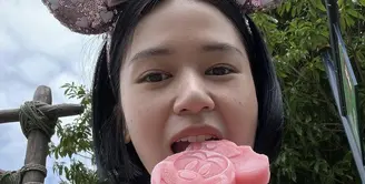 Masih di Disneyland, Laura Basuki tampil tanpa makeup sambil menggigit ice cream. Tampil dengan bondu Minnie Mouse pinknya. (@laurabas)