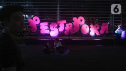 Sejumlah pengunjung duduk di bangunan instalasi pada acara "Pestapora 2022" di Gambir Expo Kemayoran, Jakarta, Sabtu (24/9/2022). Pada acara pertunjukan musik Indonesia yang berlangsung 23-25 September 2022 tersebut menghadirkan enam panggung pertunjukan dengan menampilkan berbagai musisi tanah air. (Liputan6.com/Herman Zakharia)