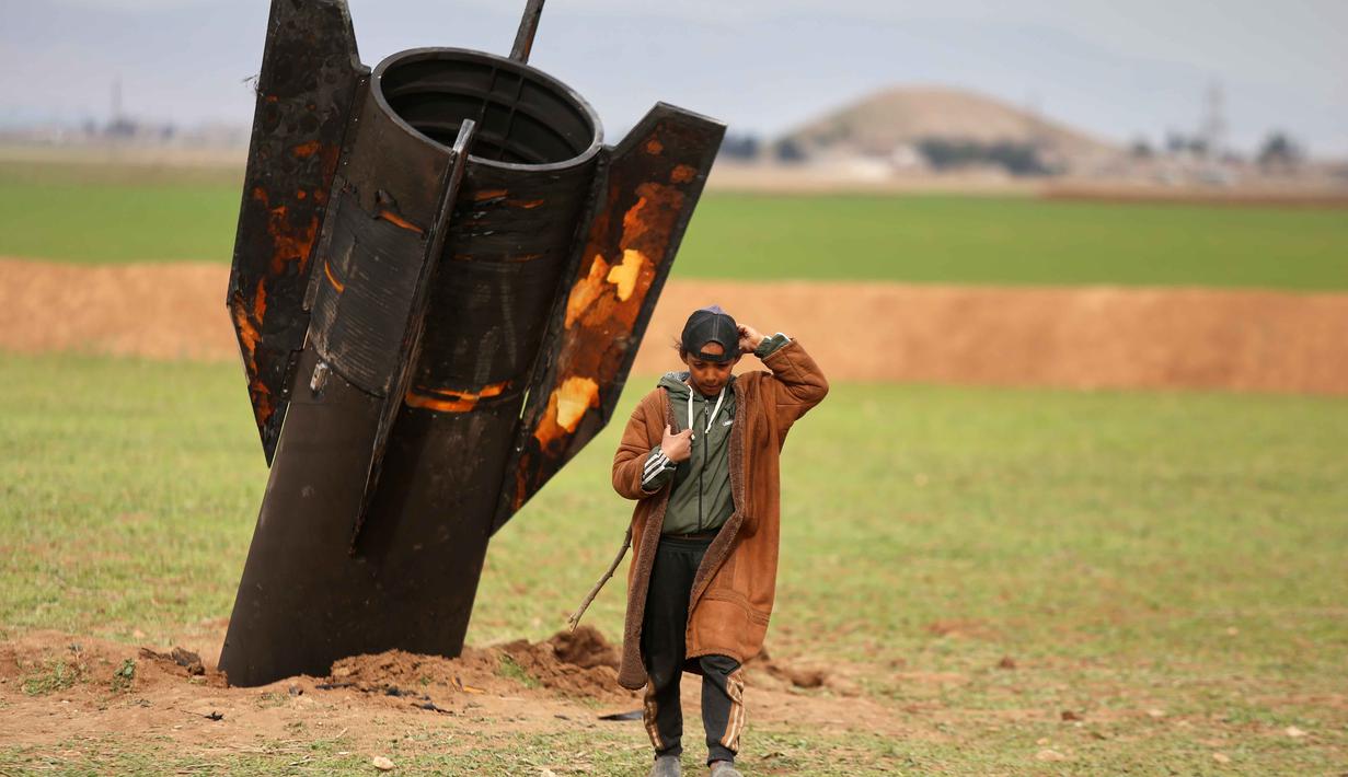 Otoritas setempat memperingatkan bagi warga terkait bahaya besar paparan langsung dengan bahan peledak yang belum meledak ini. Tampak dalam foto, seorang anak gembala berjalan menjauhi proyektil rudal Iran yang belum meledak di lapangan terbuka di pinggiran Qamishli, Suriah timur, Rabu 4 Maret 2026. (AP Photo/Baderkhan Ahmad)
