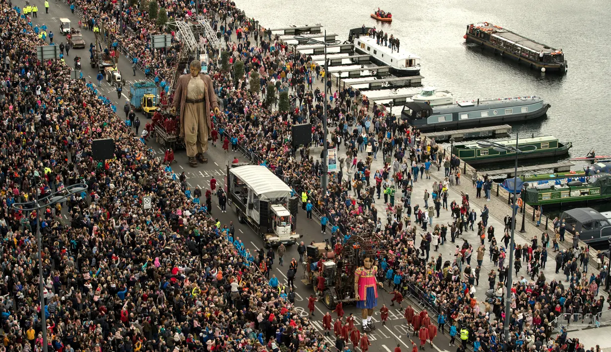 Boneka raksasa bernama Giant dan Little Girl Giant berjalan melewati dermaga di Liverpool, Inggris, Minggu (7/10). Boneka itu karya dari kelompok teater jalanan Prancis, Royal de Luxe dengan ciri khas aktor berupa Boneka Super Besar. (OLI SCARFF/AFP)