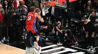 Mac McClung melompati dua orang yang bergendongan di kontes slam dunk NBA All-Star 2023 (AFP)