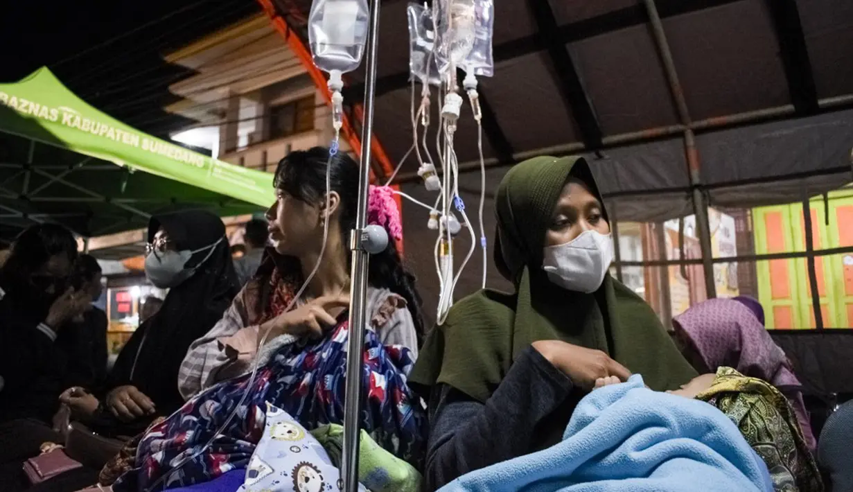 Pasien dievakuasi ke tenda darurat yang didirikan di luar RSUD Sumedang setelah atap dan dinding rusak akibat gempa magnitudo 4,8 di Sumedang, Jawa Barat, Senin (1/1/2024). (Timur MATAHARI/AFP)