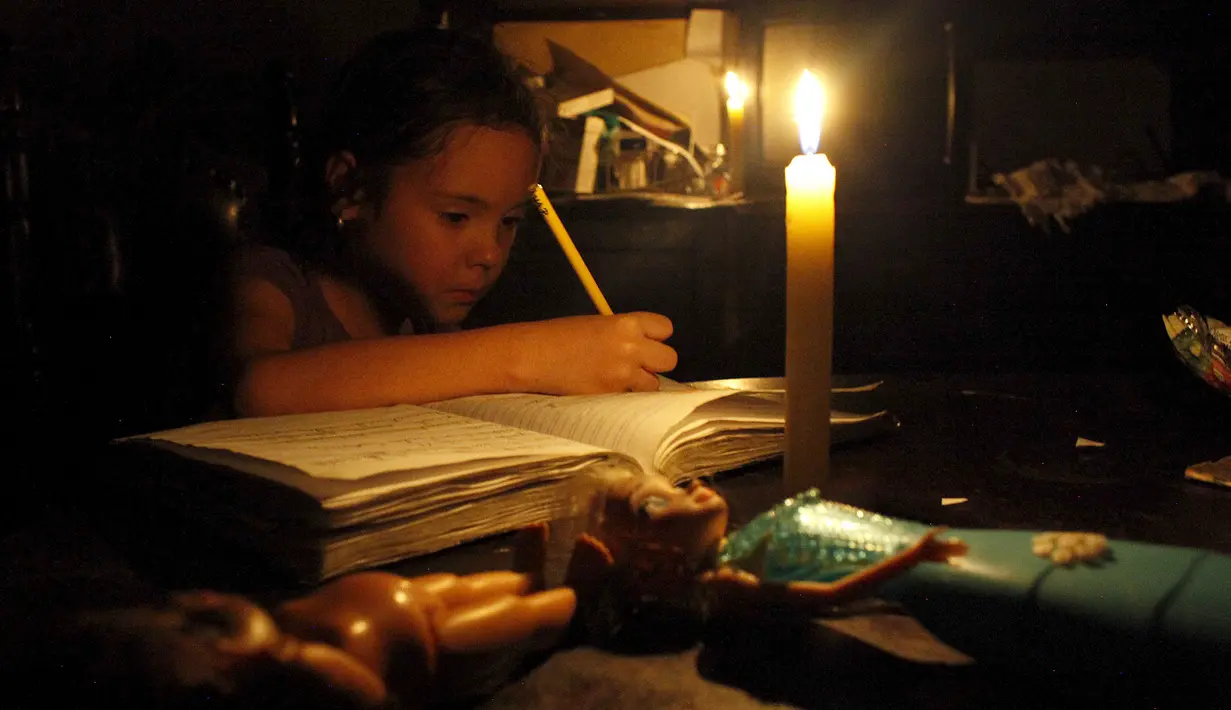 Seorang anak belajar dengan menggunakan lilin akibat pemadaman listrik di San Cristobal, Venezuela, Senin (25/4). Venezuela menerapkan pemadaman listrik selama empat jam sehari untuk menghadapi krisis energi yang memburuk. (REUTERS/Carlos Eduardo Ramirez)