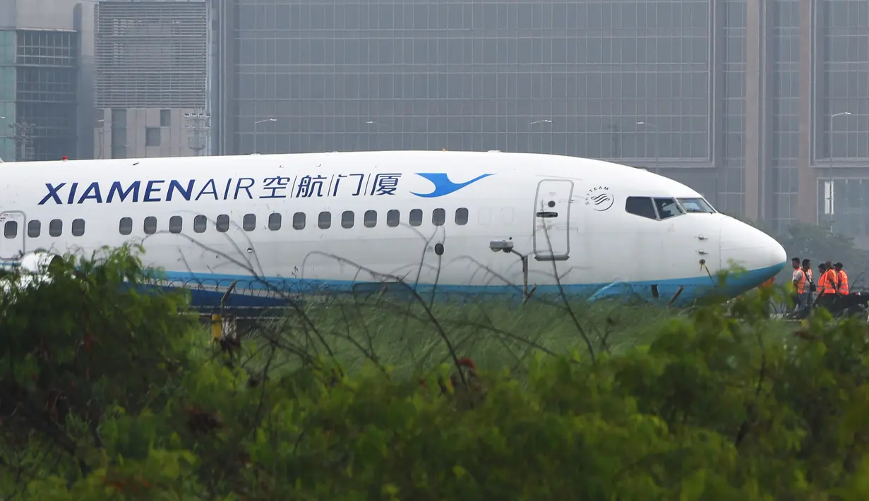 Petugas melihat pesawat milik XiamenAir yang tergelincir dari landasan di bandara internasional Manila, Filipina, Kamis (16/8). Insiden ini sempat memaksa penutupan sebagian Bandara Manila, khususnya landasan utama. (AFP/TED ALJIBE)