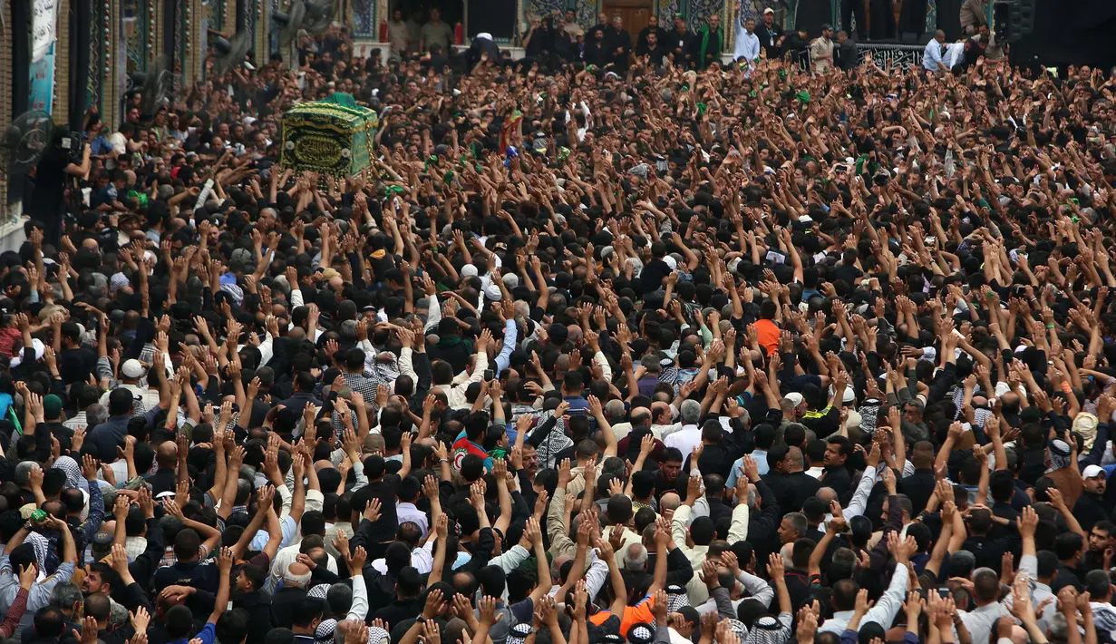Ribuan umat Syiah Irak menyaksikan peti jenazah yang menyimbolkan Musa al-Kadhim di Kadhimiya, distrik utara Baghdad, Irak (23/4). Ribuan peziarah mendatangi tempat tersebut untuk memperingati wafatnya Musa al-Kadhim. (AFP/Sabar Arar)