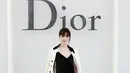 Orm tampil elegan dengan blazer putih dihiasi bros bunga di kerah. Dipadukan dress velvet hitam, tas motif houndstooth hitam-putih, dan heels putih [dok. Dior]