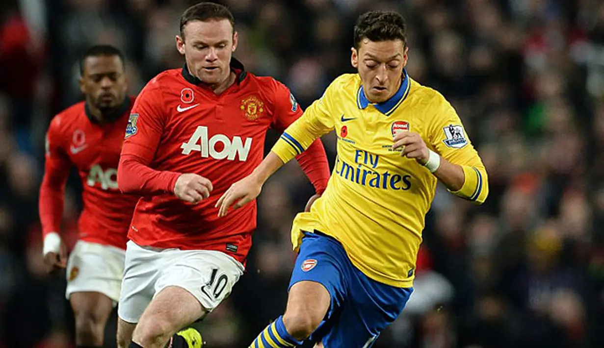 Gelandang Arsenal Mesut Ozil (kanan) berebut bola dengan Wayne Rooney saat pertandingan sepak bola Liga Inggris antara Manchester United melawan Arsenal di Stadion Old Trafford, Manchester (10/11/13) waktu setempat (Foto: AFP/Paul Ellis)