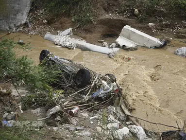 Sebuah mobil tergeletak di sungai setelah hujan lebat di Thessaloniki, Yunani utara, Sabtu, 17 Juni 2023. Rumah-rumah terendam banjir dan pohon-pohon tumbang serta mobil-mobil hanyut setelah hujan lebat di banyak pinggiran kota di bagian utara. (AP Photo/Giannis Papanikos)