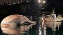 Bangkai paus berukuran besar (kiri) di pelabuhan Sorrento saat ditarik oleh penjaga pantai Italia menuju pelabuhan Napoli pada Rabu (20/1/2021). Mamalia yang mati itu terlihat di laut pada Minggu, 17 Januari 2021 dekat tujuan wisata populer Sorrento oleh penjaga pantai. (HO/GUARDIA COSTIERA/AFP)