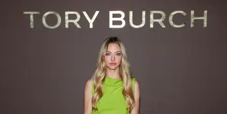 Amanda Seyfried hadir dengan koleksi Resort 2027. Padanan brushed wool top, patent leather skirt, woven raffia belt, dengan the suede Bunny Knot shoulder bag, dan peep-toe pumps. / Foto: Tory Burch.