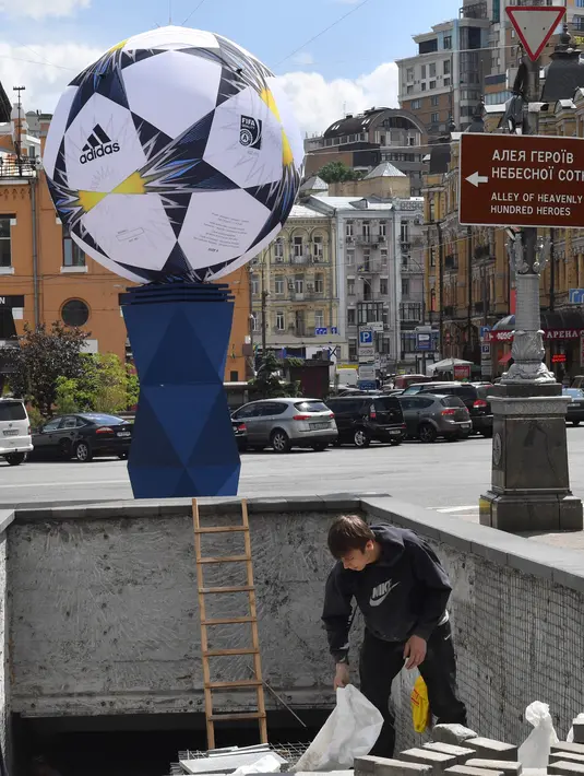 Seorang pekerja memperbaiki patung bola di Kiev, Ukraina (22/5). Kota Kiev akan menjadi tuan rumah penyelenggaraan final Liga Champions antara Real Madrid dan Liverpool di Olimpiyskiy Stadion. (AFP Photo/Sergei Supinsky)