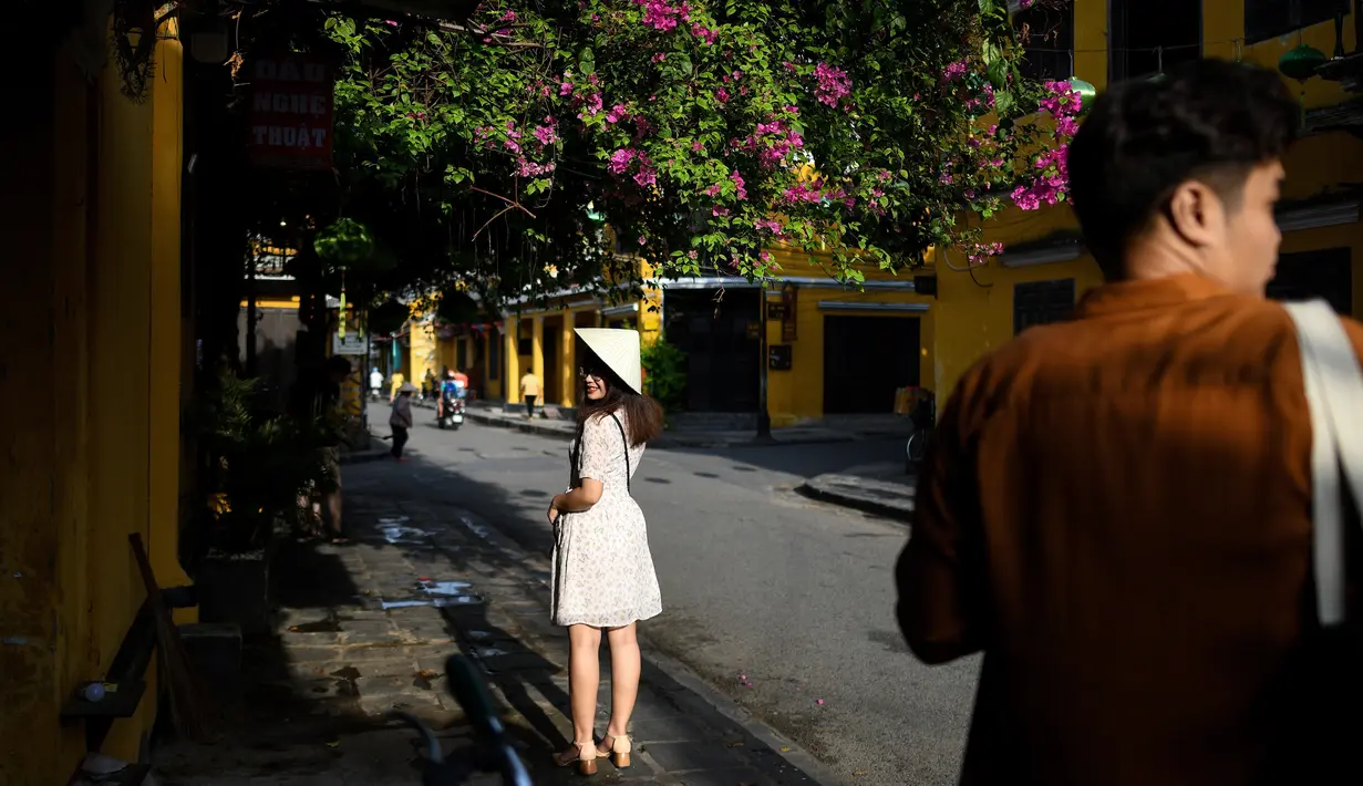 Gambar pada 14 September 2019 memperlihatkan seorang turis berpose di kota tua Hoi An, Vietnam. Kota Tua Hoi An merupakan destinasi wisata yang cukup populer di Vietnam, didukung oleh statusnya sebagai salah satu Unesco World Heritage Site. (Manan VATSYAYANA/AFP)