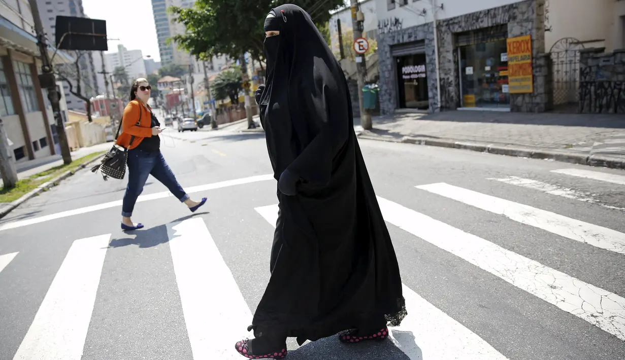 Gisele Marie melintasi jalan setelah latihan di sebuah studio, Sao Paulo (15/9/2015). Banyak orang disekitarnya terkejut melihat seorang wanita Muslim yang menggunakan Burka memainkan musik metal. (REUTERS/Nacho Doce)