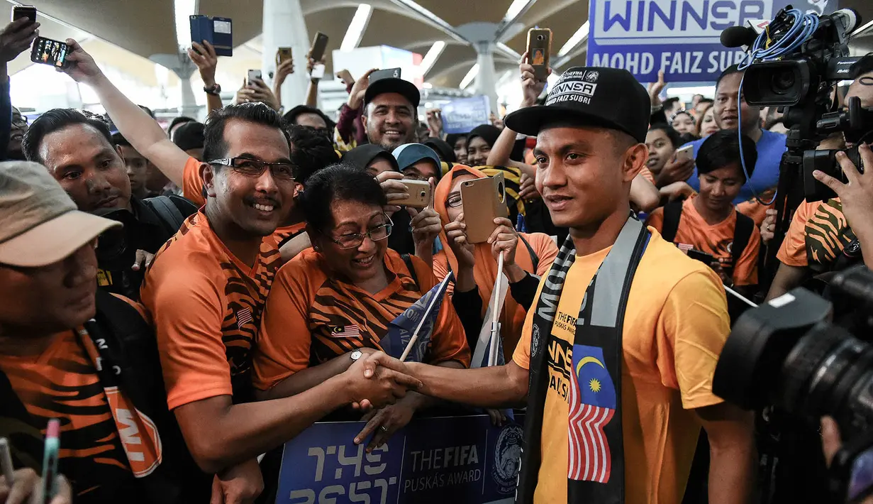 Pesepak bola Malaysia, Faiz Subri, disambut warga negeri jiran saat tiba di Bandara International Kuala Lumpur, Malaysia, Rabu (11/1/2017). Pemain Penang FA ini menjadi pesepak bola Asia pertama yang meraih FIFA Puskas Award. (AFP/Mohd Rasfan)