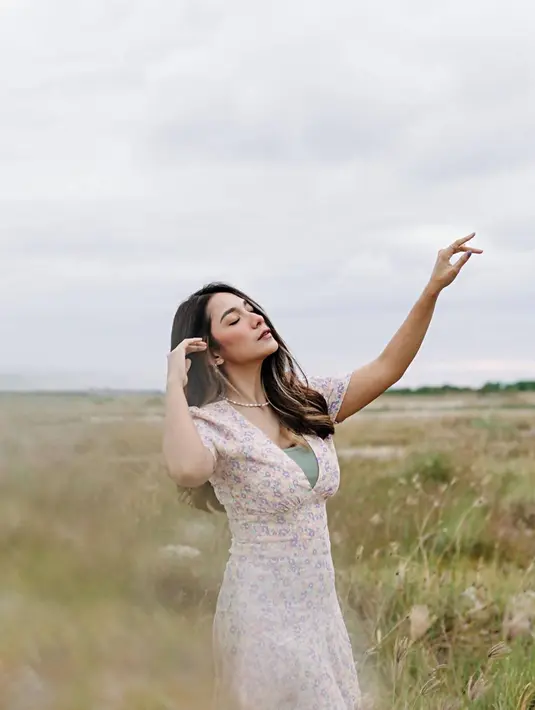 Menjadi model video klip, tidak jarang Dinda Kirana mengabadikan berbagai posenya di tempat-tempat yang indah. Seperti halnya saat di padang rumput ilalang ini. Ia pun tampil luwes dengan dress floralnya yang senada dengan suasana di sekitarnya. (Liputan6.com/IG/@dindakirana.s)