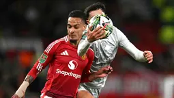 Pemain Manchester United, Antony (kiri) berebut bola dengan pemain Barnsley, Corey O'Keeffe pada laga Carabao Cup 2024/2025 di Old Trafford, Manchester, Inggris, Rabu (18/09/2024) WIB. (AFP/Paul Ellis)