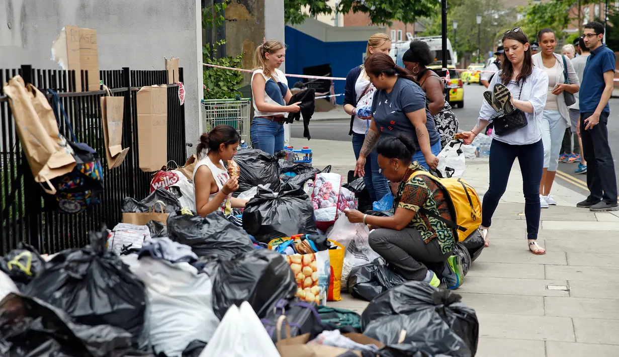 Relawan saling mengoper kardus yang berisikan bantuan untuk para korban kebakaran apartemen di Kensington, London, (15/6). Relawan memberikan bantuan bahan makanan dan pakaian untuk para korban kebakaran Grenfell Tower. (AP Photo/Alastair Grant)