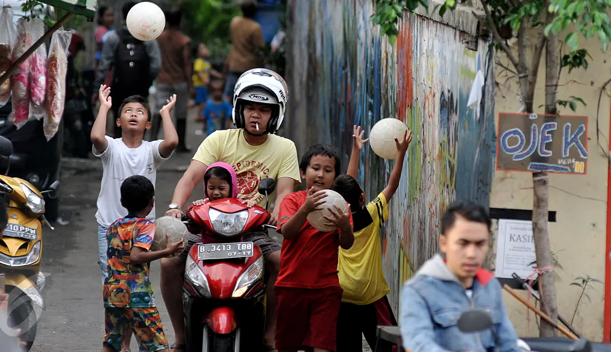 Pengendara motor melintas ketika sejumlah bocah bermain bola di gang kecil kawasan Benhil, Jakarta, Rabu (10/6). Gang kecil itu dimanfaatkan untuk bermain dikarenakan minimnya sarana bermain khususnya lapangan bola di Jakarta. (Liputan6.com/Johan Tallo)