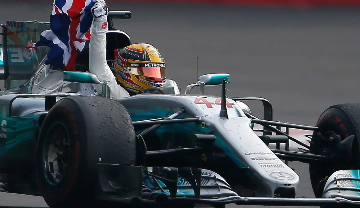 Pembalap asal Inggris dari tim Marcedes, Lewis Hamilton membawa bendera negaranya merayakan kemenangannya meraih juara dunia F1 untuk yang ke empat kalinya di Autodromo Hermanos Rodrigue, Meksiko (29/10). (AP Photo / Eduardo Verdugo)