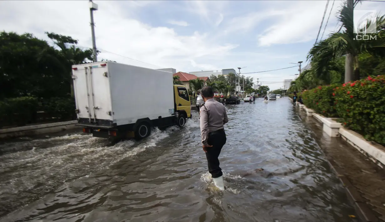 Petugas kepolisian mengecek lokasi banjir rob di kawasan Muara Baru, Jakarta, Rabu (6/11). Banjir Rob akibat laut pasang ini, membuat sejumlah aktivitas warga terganggu. Termasuk aktivitas di pasar ikan terhenti. (Liputan6.com/Faizal Fanani)