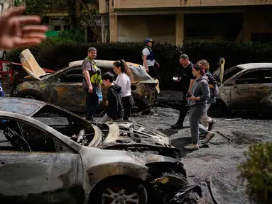 Warga dan pasukan keamanan Israel memeriksa lokasi yang terkena serangan rudal Iran di Petah Tikva, Israel, Selasa 31 Maret 2026. Serangan rudal balistik Iran kembali menghantam wilayah Petah Tikva, Israel. (AP Photo/Ohad Zwigenberg)