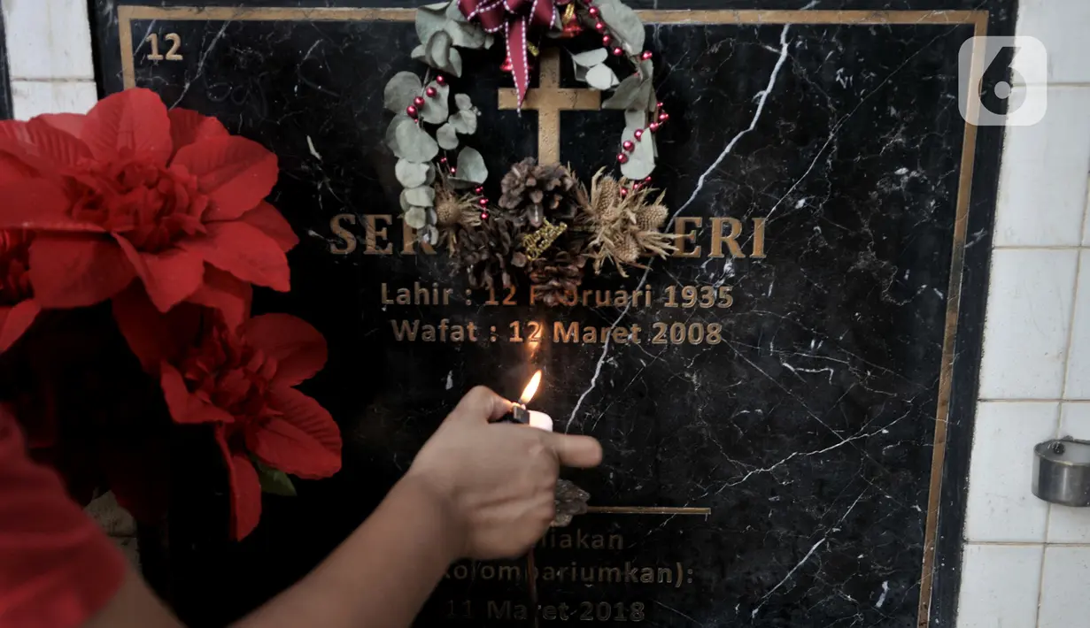 Keluarga menyalakan lilin di salah satu makam bersusun atau kolumbarium saat berziarah ke kompleks pemakaman Paroki Gereja St Servatius, Kampung Sawah, Bekasi, Jawa Barat, Kamis (26/12/2019). (merdeka.com/Iqbal Nugroho)
