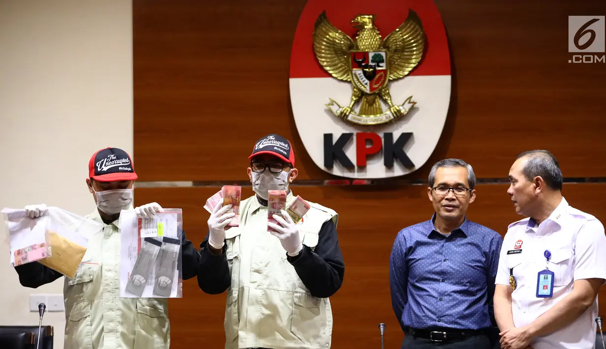 Petugas menunjukkan barang bukti Rp1,2 miliar disaksikan Wakil Ketua KPK Alexander Marwata dan Irjen Kemenkum HAM Jhoni Ginting saat keterangan pers OTT penanganan perkara penyalahgunaan izin tinggal Kantor Imigrasi Kelas I Mataram, NTB di Gedung KPK, Jakarta (28/5/2019). (Liputan6.com/Johan Tallo)