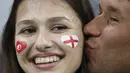 Seorang suporter Inggris mencium kekasihnya saat negaranya melawan Tunisia pada laga grup G Piala Dunia di Volgograd Arena, Volgograd, Senin (18/6/2018). Cerita sepenggal kisah romantis saat Piala Dunia 2018 Rusia. (AFP/Philippe Desmazes)