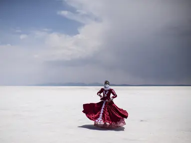 Seorang penari berpose dengan kostum tradisional di Salar de Uyuni, dataran garam terbesar di dunia, di Uyuni, Bolivia, pada 7 November 2020. Dikenal sebagai dataran garam terluas di dunia karena Salar de Uyuni memiliki luas sekitar 4.086 kilometer persegi. (RONALDO SCHEMIDT/AFP)