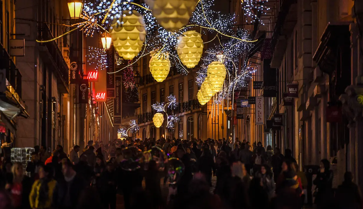 Orang-orang berjalan di bawah lampu Natal di Chiado di Lisbon (17/12). (AFP Photo/Patricia De Melo Moreira)