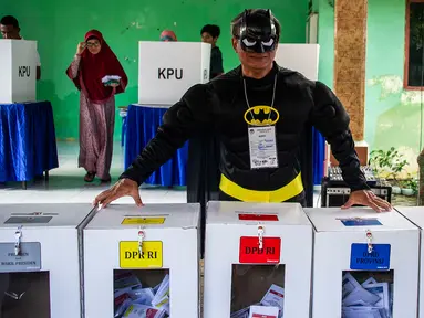 Petugas Kelompok Penyelenggara Pemungutan Suara (KPPS) berkostum superhero Batman menjaga kotak suara Pemilu 2019 di sebuah TPS di Surabaya, Jawa Timur, Rabu (17/4). Petugas KPPS rela berdandan ala superhero demi mengajak dan menarik pemilih agar mau datang ke TPS. (Juni Kriswanto/AFP)