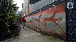 Warga berjalan dekat mural yang menghiasi tembok rumah warga RT 02/RW 07 Kampung Warna-warni, Kelurahan Pengadegan, Jakarta Selatan, Selasa (10/12/2019). Mural tersebut sebagai bentuk kesadaran warga untuk menciptakan kampung yang enak dipandang, bersih, aman, dan nyaman. (merdeka.com/Imam Buhori)