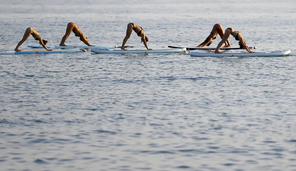 Sejumlah wanita berbikini melakukan yoga Float Metta dengan papan seluncur di Laut Adriatic, Kroasia, Kamis (6/8/2015). (REUTERS/Pawel Kopczynski)
